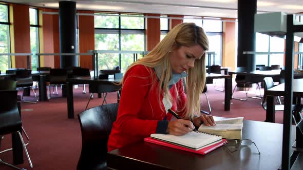 Mature Student with Reading Glasses Studying at Library Desk