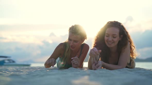 Girls Smiling While Writing on Sand Thailand