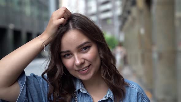 Close-up Portrait of a Young Dark-haired Woman , She Is on a City Street in the Afternoon and Posing