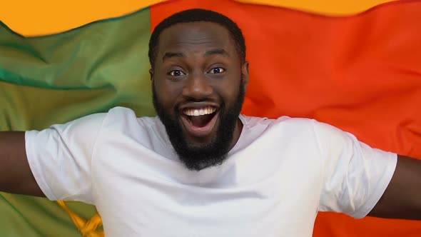 Happy Black Male Holding Flag of Portugal on Yellow Background, Supporting Team