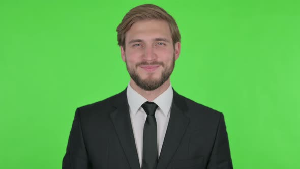 Smiling Young Businessman on Green Background