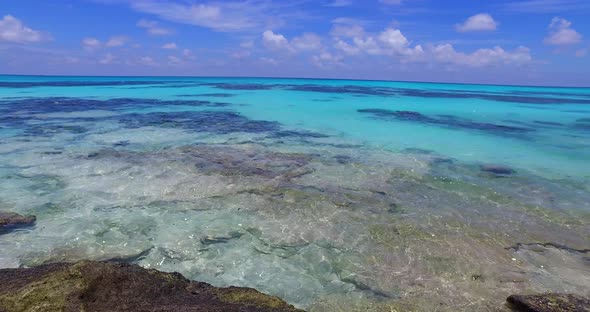 Wide angle flying clean view of a white paradise beach and aqua blue water background in colorful 4K