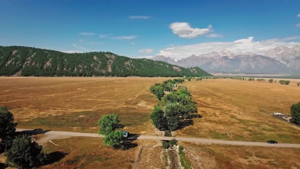 Aerial footage shows a lone trailer that rides across the golden prairie at Mormon Row, Wyoming, USA