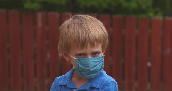 Portrait of a little boy unhappy to be wearing a protective face mask.