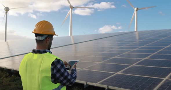 Young man working with digital tablet at renewable energy farm