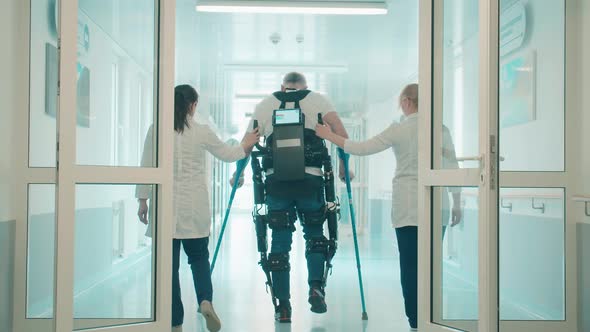 Doctors are Helping Male Patient to Walk in the Exosuit