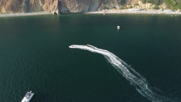 Happy People Swim on Air Mattress Behind a High Speed Water Bike