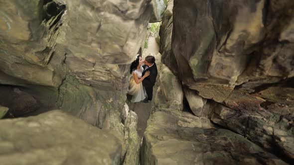 Groom with Bride Standing in Cave of Mountain Hills. Wedding Couple in Love