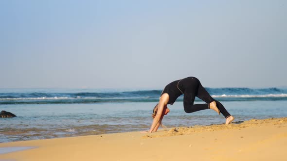 Girl in Tracksuit Does Pilates Exercises on Ocean Beach