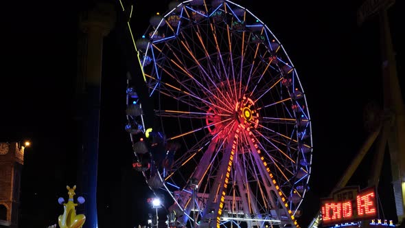 Colorful illuminated Ferris wheel, fun toys and adrenaline filled instruments in luna park.