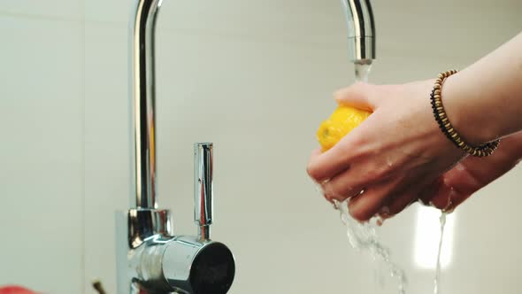 Woman's Hands Wash a Lemon Under the Tap with Water