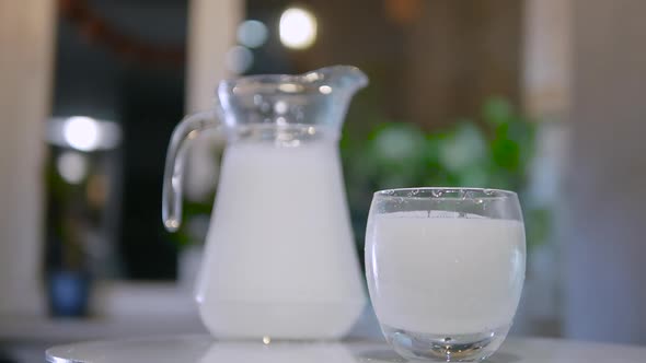 Slow Motion Glass With Fresh Milk On Bokeh Background. A Natural Dairy Product In A Jug