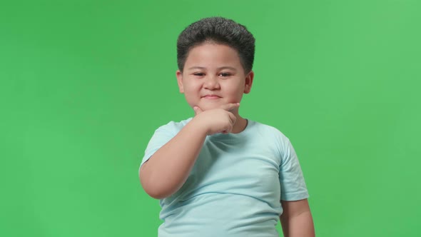 Asian Little Boy Touching Her Hair While Looking At Camera Like A Mirror On Green Screen In Studio alt