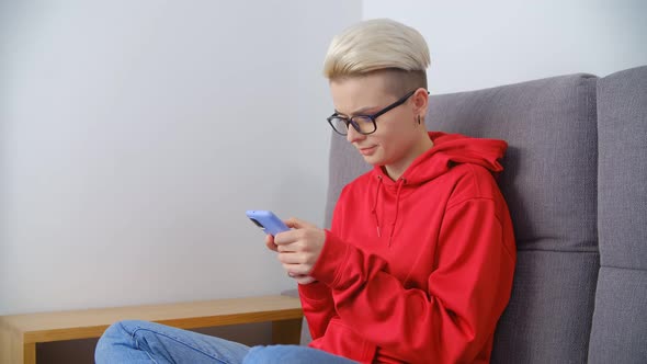 Young white female browsing phone while sitting on sofa at home in 4k stock video clip
