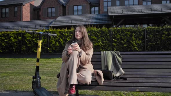 Woman rest and drinks coffee with her scooter next