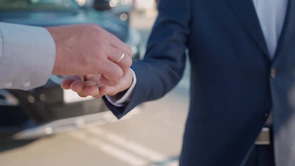 Businessman in Suit Picks Up a Car at the Dealership Dealer Hands Over the Keys to a New Car to the