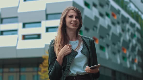 Good Looking Girl with Long Brown Hair Looking at Her Phone Typing and Smiling