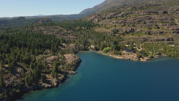 Aerial pan right of Epuyen lake surrounded by pine tree forest and mountains, Patagonia Argentina
