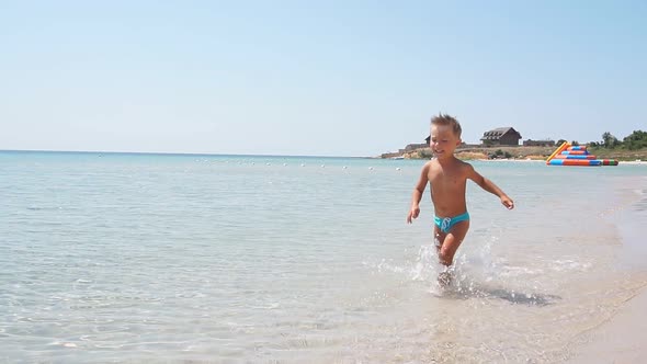 Boy Runs Along the Coast of the Azure Sea Creating Sea Spray, Slow Motion