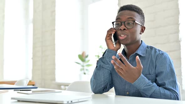 Smiling Young African Man Talking on Smartphone in Office