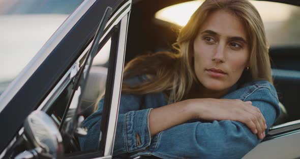 Beautiful woman in a vintage car at sunset