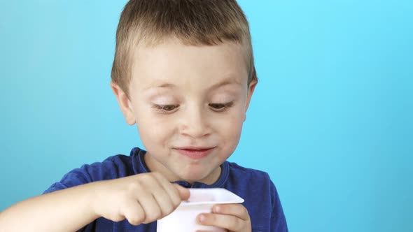 Little boy eatiing yogurt on blue background