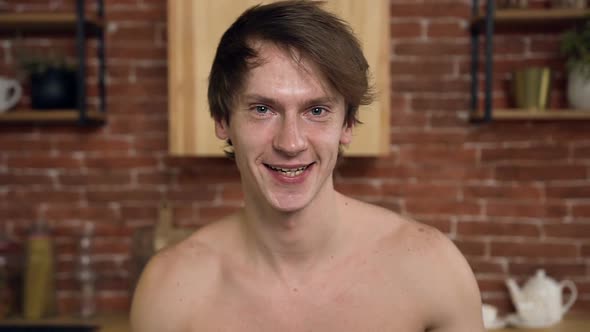 Portrait shot of man looking to the camera and start eating salad in the kitchen.