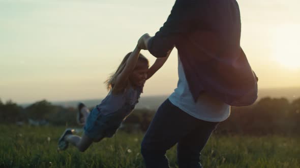 Dad playing with daughter at the meadow during the sunset. Shot with RED helium camera in 4K.