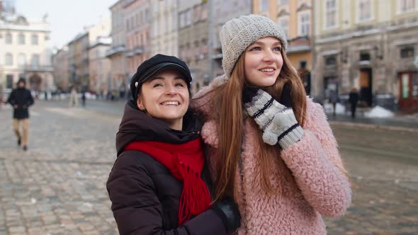 Two Smiling Women Tourists Walking Together on City Street Family Couple Talking Embracing