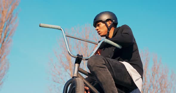 A Tired Darkskinned Man in Helmet is Resting Sitting on Low Bike He Has Lost