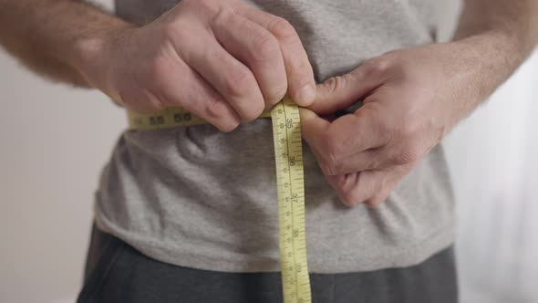 Closeup of Male Hands Measuring Waist 27 Inches and Showing Thumb Up