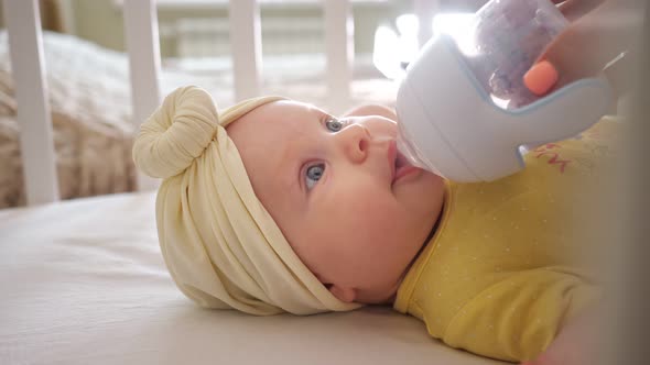 Closeup of a Little Girl in a Crib Drinking Water From a Sippy Cup