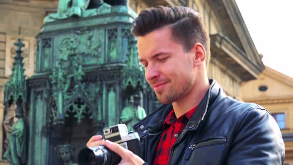 A Young Handsome Man Takes Photos with a Camera - Closeup From Below - a Monument