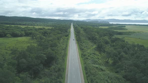 Aerial View Above Cars Driving Along Empty Countryside Road on Sunny Day