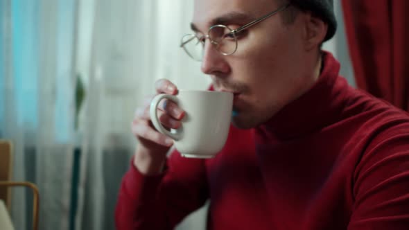 Young Man is Typing on Laptop Drinking Coffee