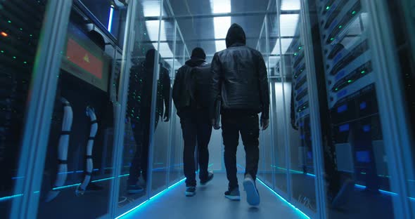 Two Hackers Walking Through Rows of Servers