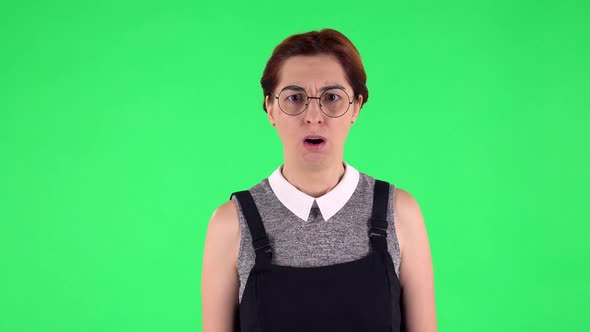Portrait of Funny Girl in Round Glasses Is Scolding and Shaking Her Index Finger. Green Screen