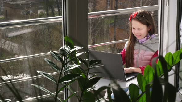 Pretty Teenager Girl Is Typing, Working on Laptop, on Open Balcony. Spring Sunny Day. Concept of