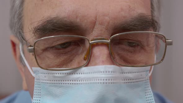 Macro Portrait of Serious Senior Man Wore in Medical Mask Looking Into Camera on Background