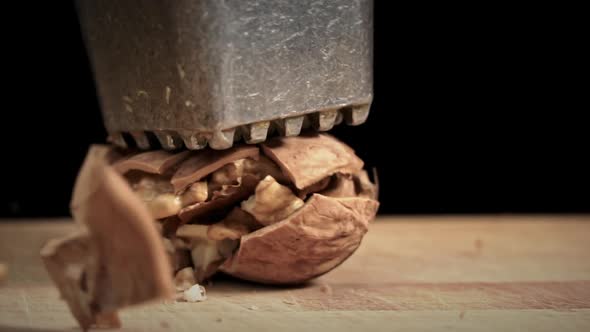 Hammer Breaks a Walnut in Slow Mo on a Black Background