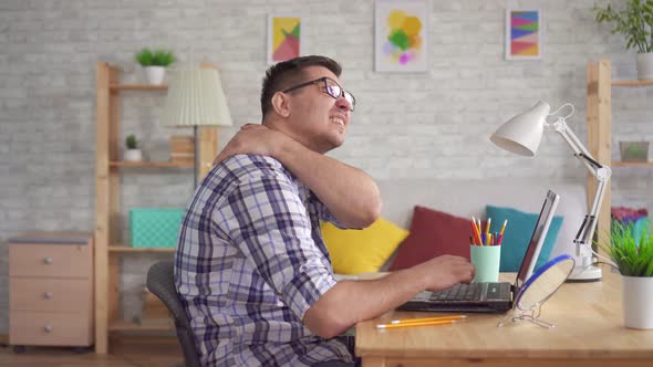 Young Woman Sitting at a Laptop Feels a Pain in the Neck and Back Due To Stooping