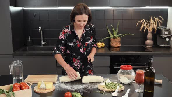 Woman cutting dough into parts with knife. Female hands cut raw dough into pieces, preparing pizza.