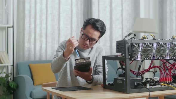 Asian Man Wearing Glasses Cleans The Graphic Card For Mining Cryptocurrency