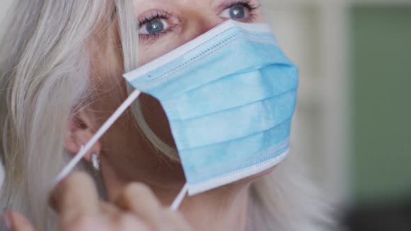 Portrait of senior caucasian woman at home removing her face mask