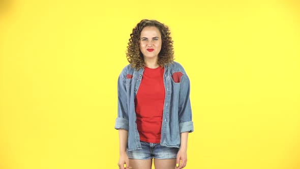 Curly Female Making a Rock Gesture, Enjoying Life and Laughing on Yellow Background at Studio