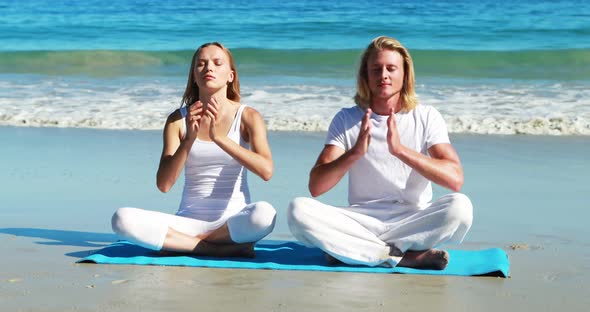 Couple performing yoga at beach