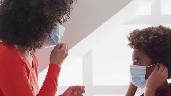 Mother wearing face mask embracing her son at home