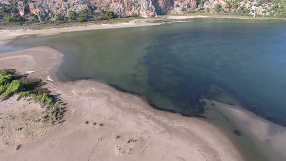 Mossy Lake Surrounded by Sandy Beach on the Rocky Hillside