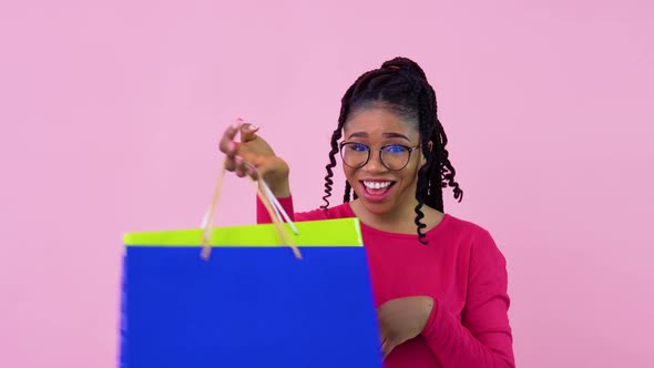 Young African American Girl in Pink Clothes Having Fun and Dancing with Paper Laminated Bags with