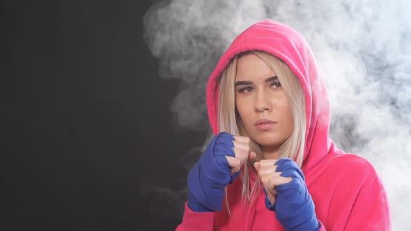 Woman in Pink Wear with Hood On, Practicing Punches While Standing in Dark Gym, Slow Motion